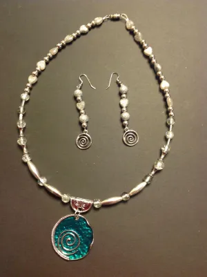 Teal pendant on a silver colored necklace and earrings.